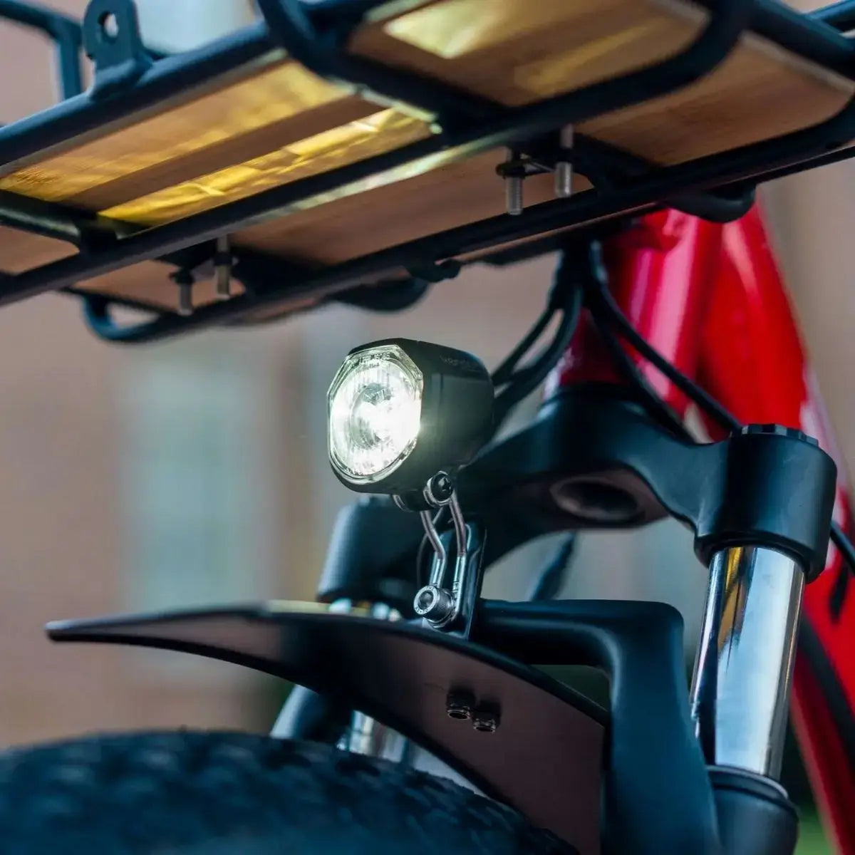 Close-up of electric trike front fork, headlight, and cargo rack with fat tire