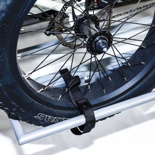 Fat tire electric trike rear wheel secured on a metal hitch rack with a strap