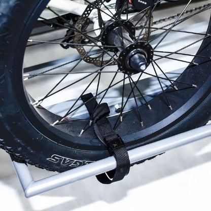 Fat tire electric trike rear wheel secured on a metal hitch rack with a strap