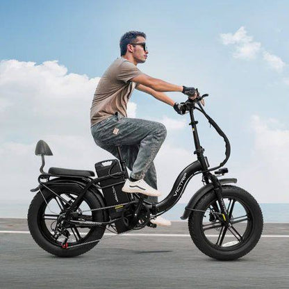 Man riding a black electric bike with fat tires on an open road, clear blue sky background